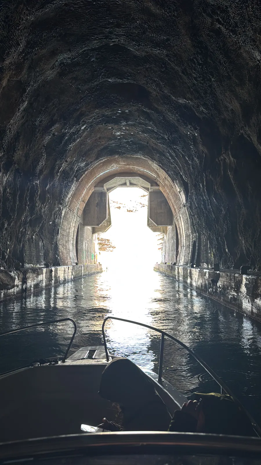 Inside a wartime submarine tunnel, looking from the boat towards the light at the exit